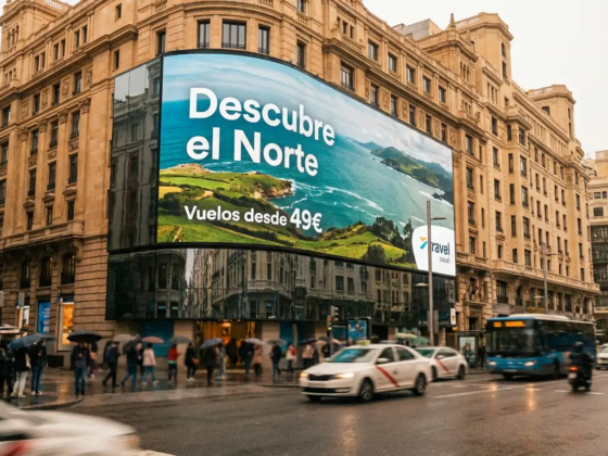 Pantalla de digital signage empotrada en edificio de la Gran Vía de Madrid mostrando anuncio turístico y pronóstico del tiempo